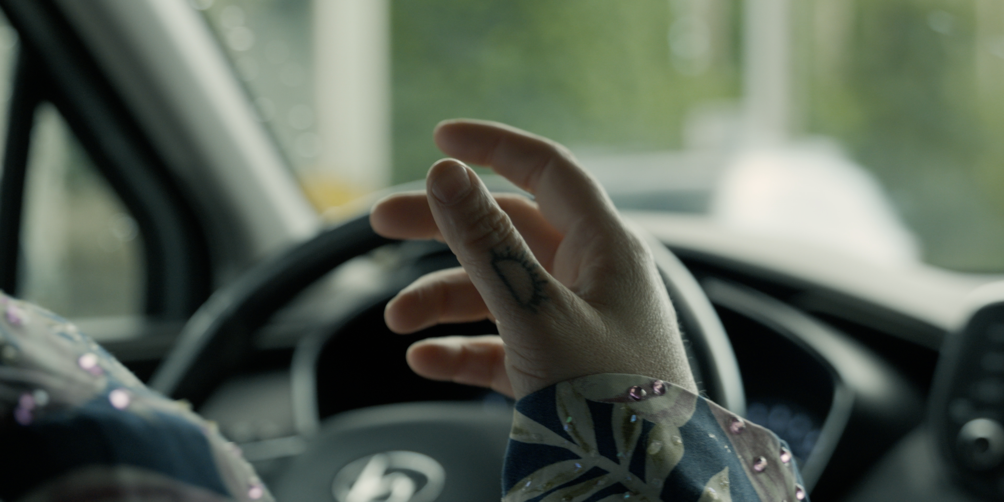 Close-up of a performer's tattooed hand inside a car in Victoria Ka Raja