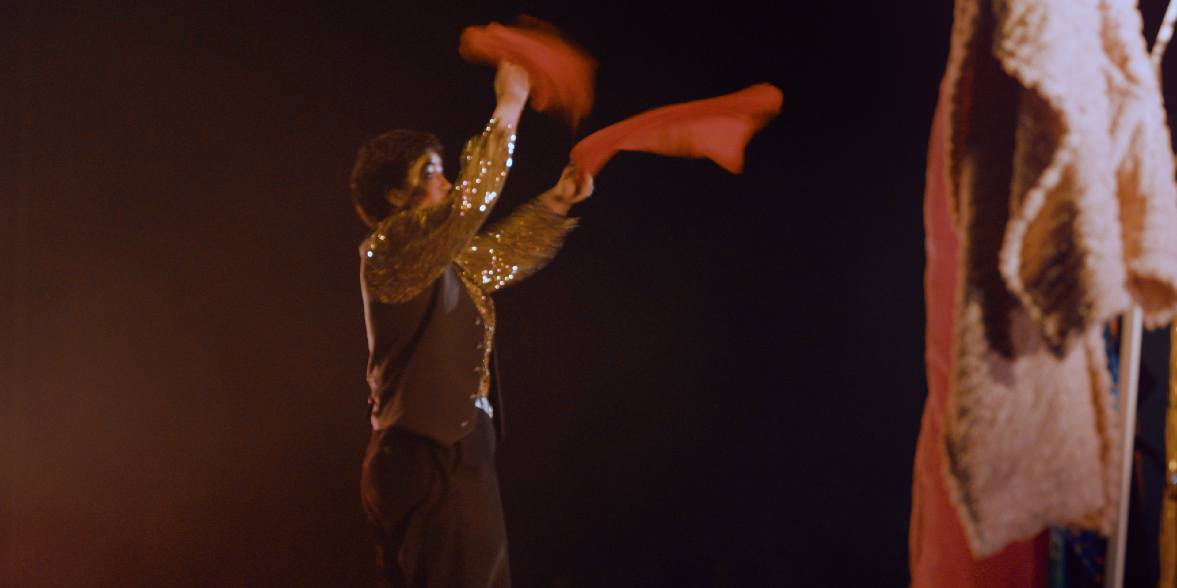Drag king performing on stage with red scarves in Victoria Ka Raja