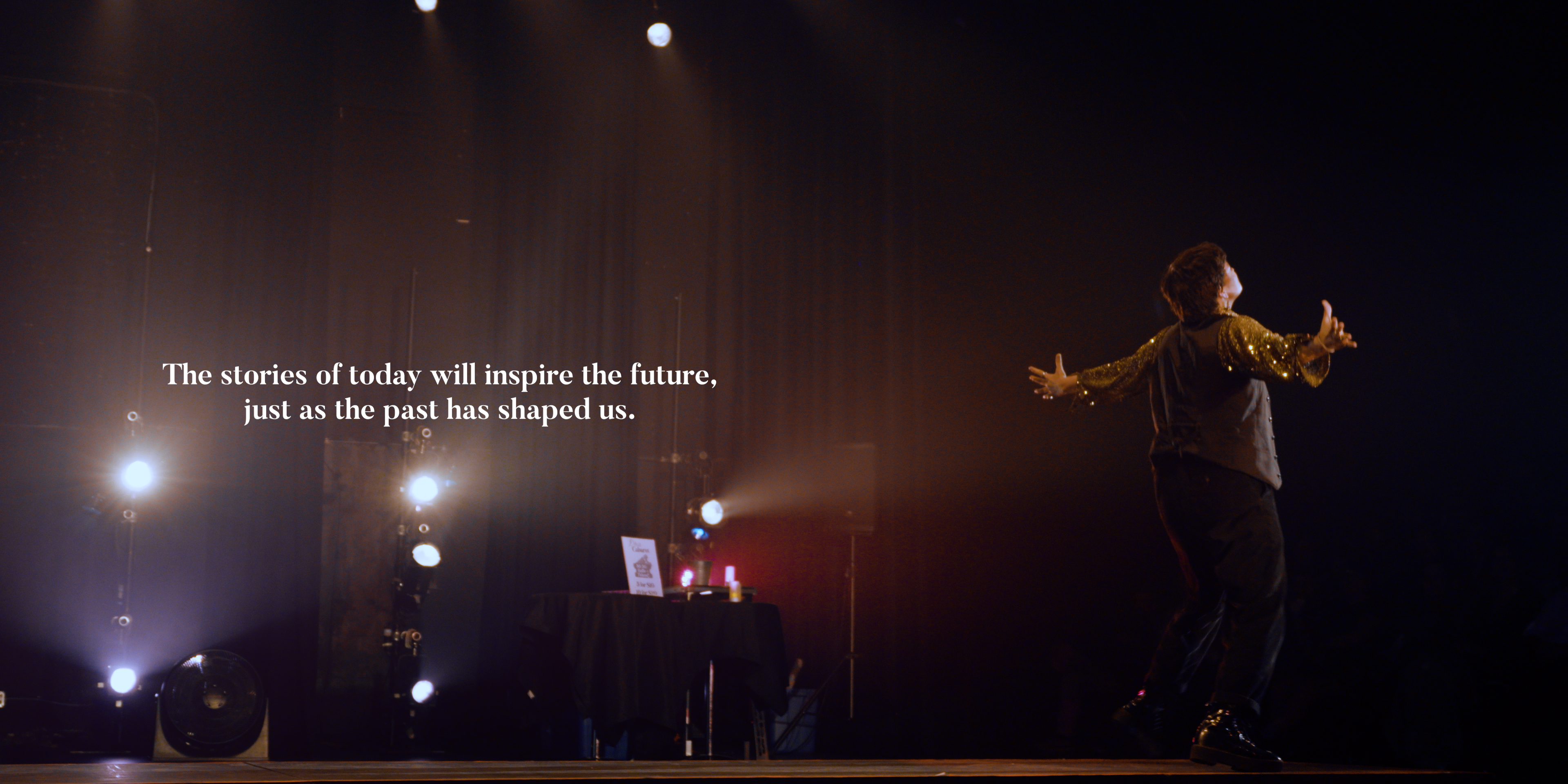 Drag king performing under stage lights beside the words The stories of today will inspire the future in Victoria Ka Raja