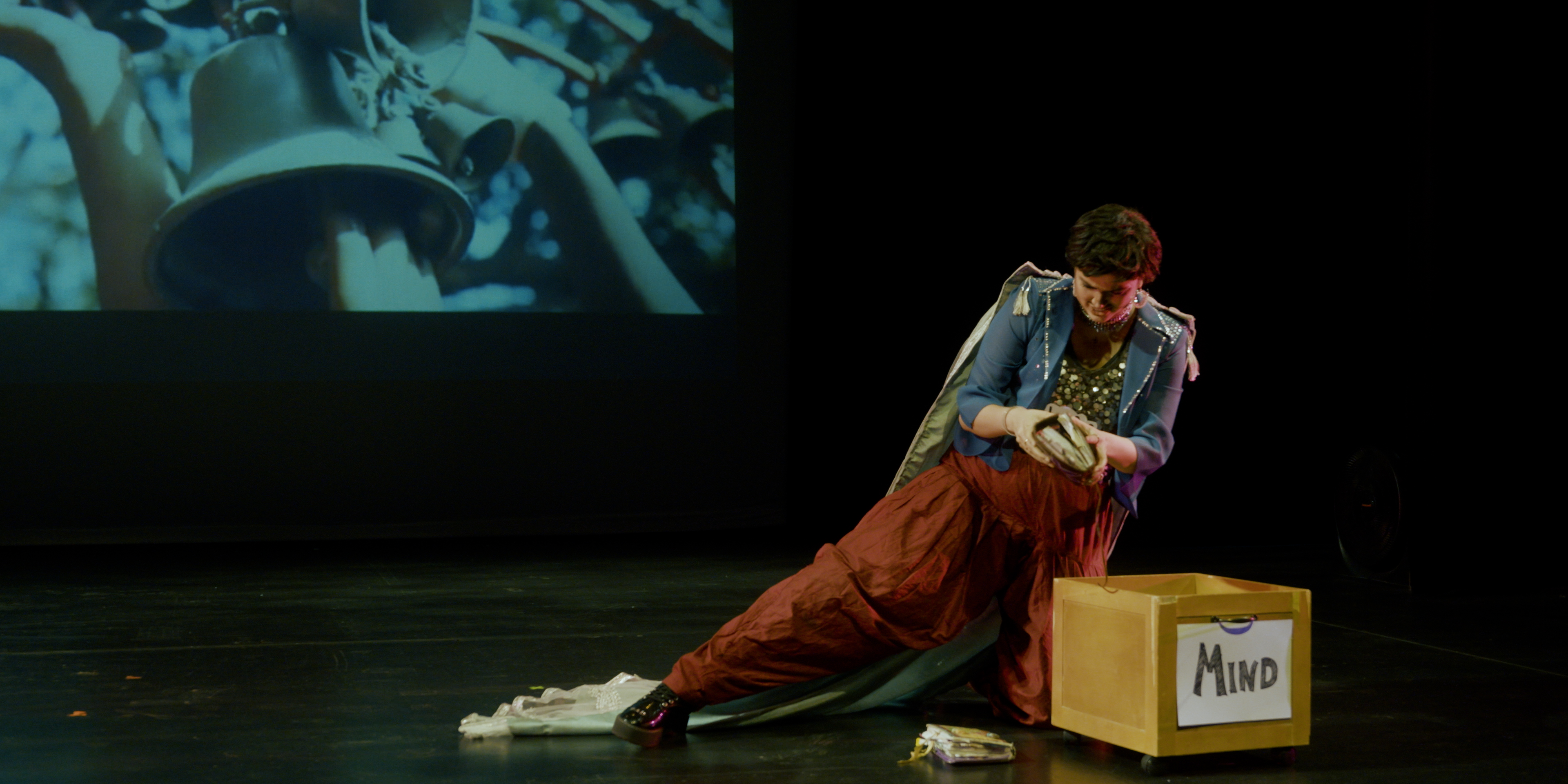 Drag king performing beside a box labelled Mind on stage in Victoria Ka Raja
