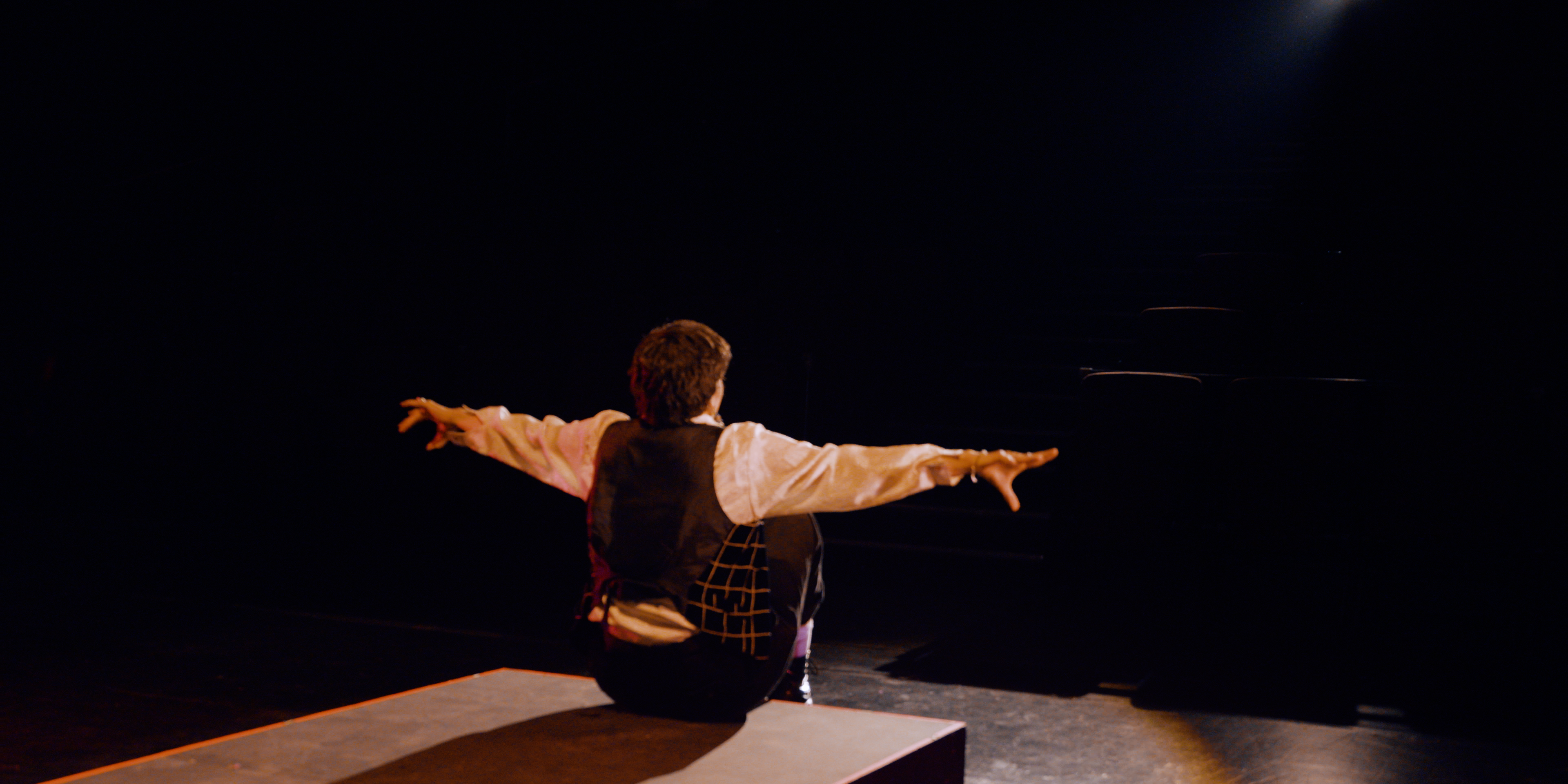 Drag king seated on stage with arms outstretched during a performance in Victoria Ka Raja